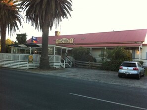 A hotel with a red roof, a signboard, and a car parked in front.