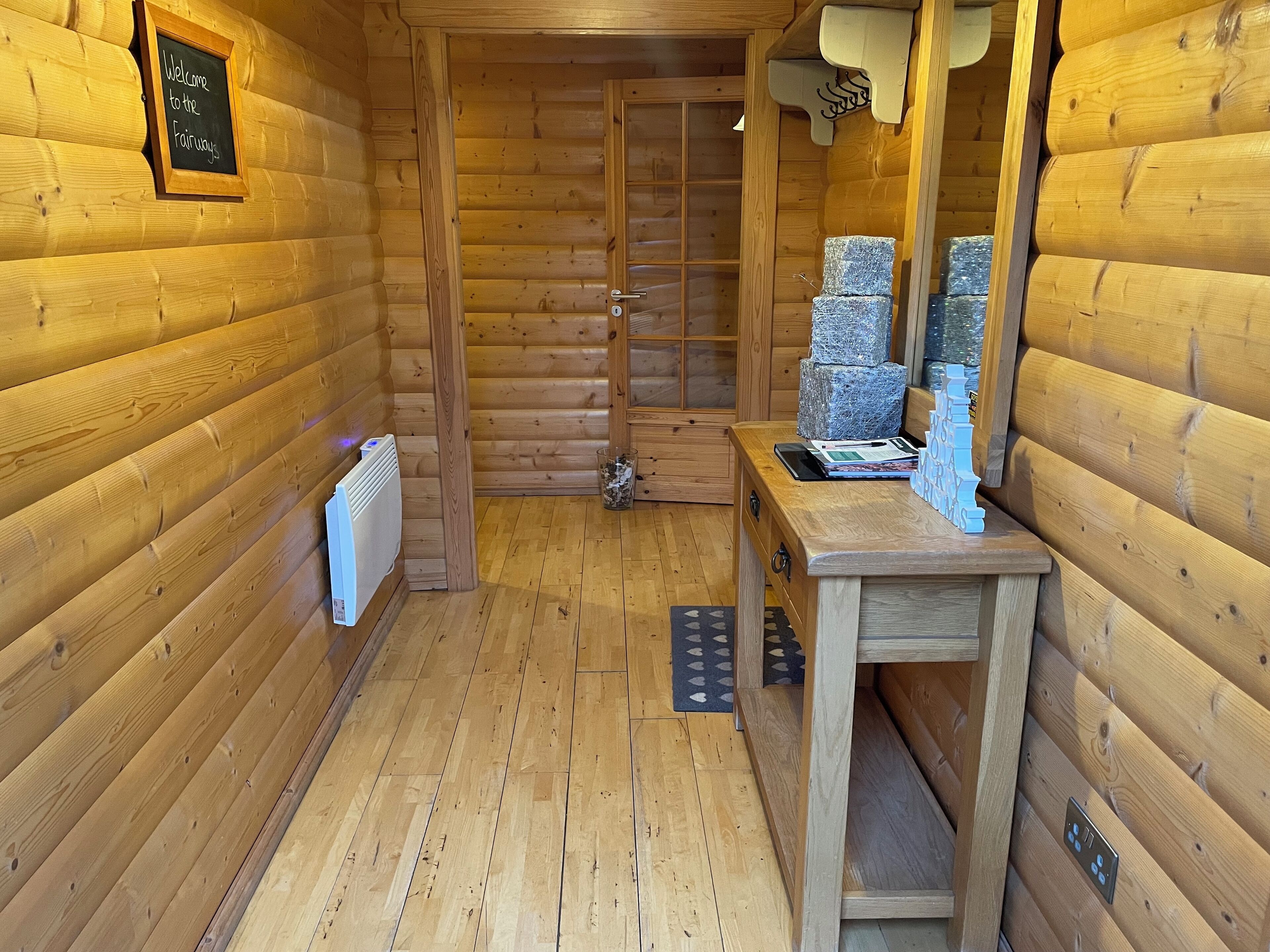 Een houten cabin met een schoolbord, een houten bank, een radiator en een deur naar een douche.