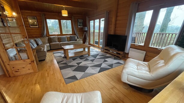 Een houten chalet inrichting met een zithoek, een bijzettafeltje en een televisie.