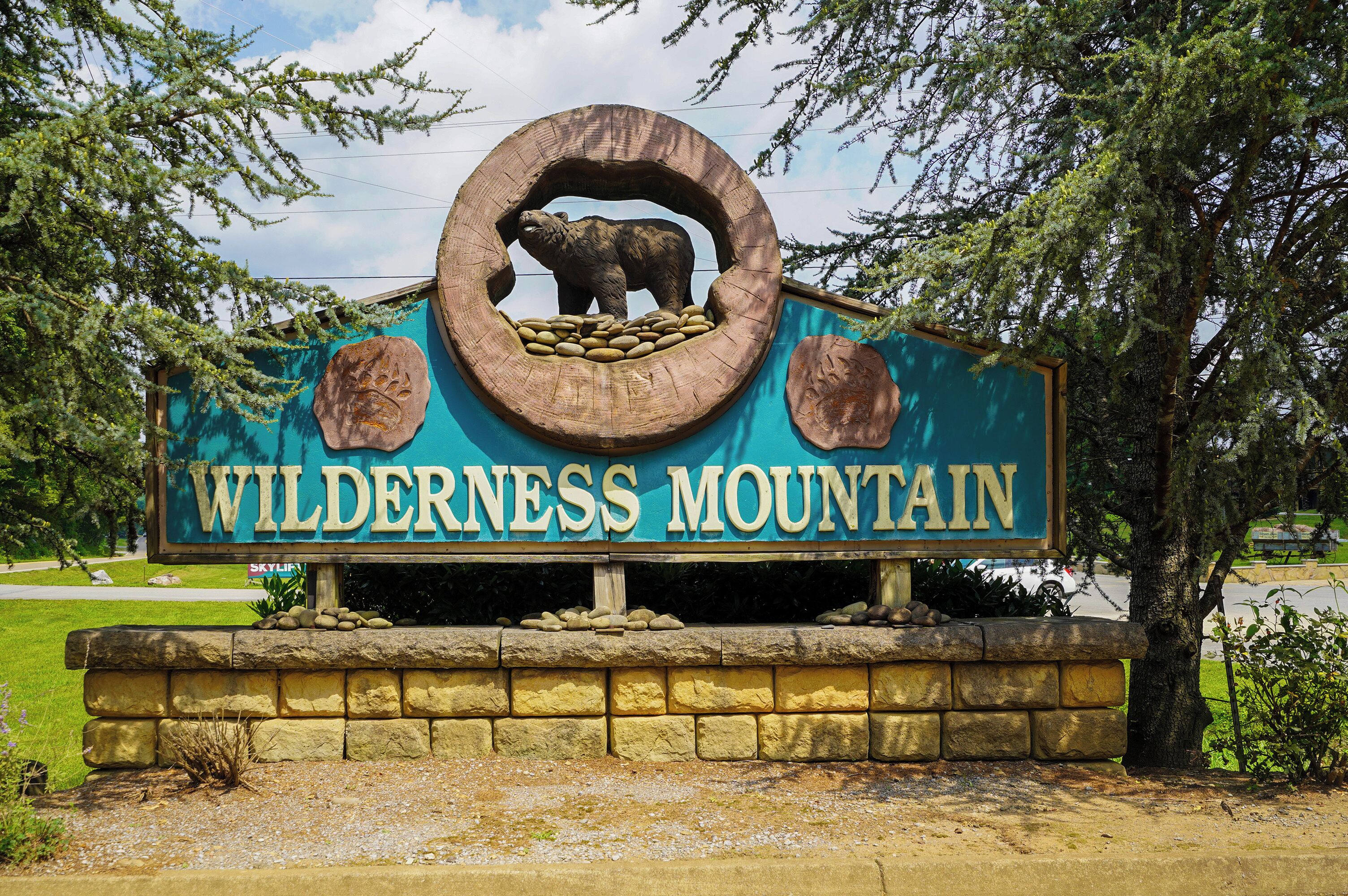 A sign with a bear and the words 'WILDERNESS MOUNTAIN' on a stone base.