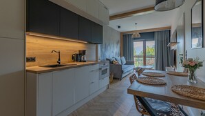 A modern kitchen with a wooden countertop, integrated appliances, and a dining area with a wooden table and woven placemats. - RentPlanet - Green Park Resort (Szklarska Poreba)