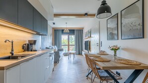 A modern kitchen with a wooden countertop, built-in cabinets, and a dining area with a wooden table and chairs. - RentPlanet - Green Park Resort (Szklarska Poreba)