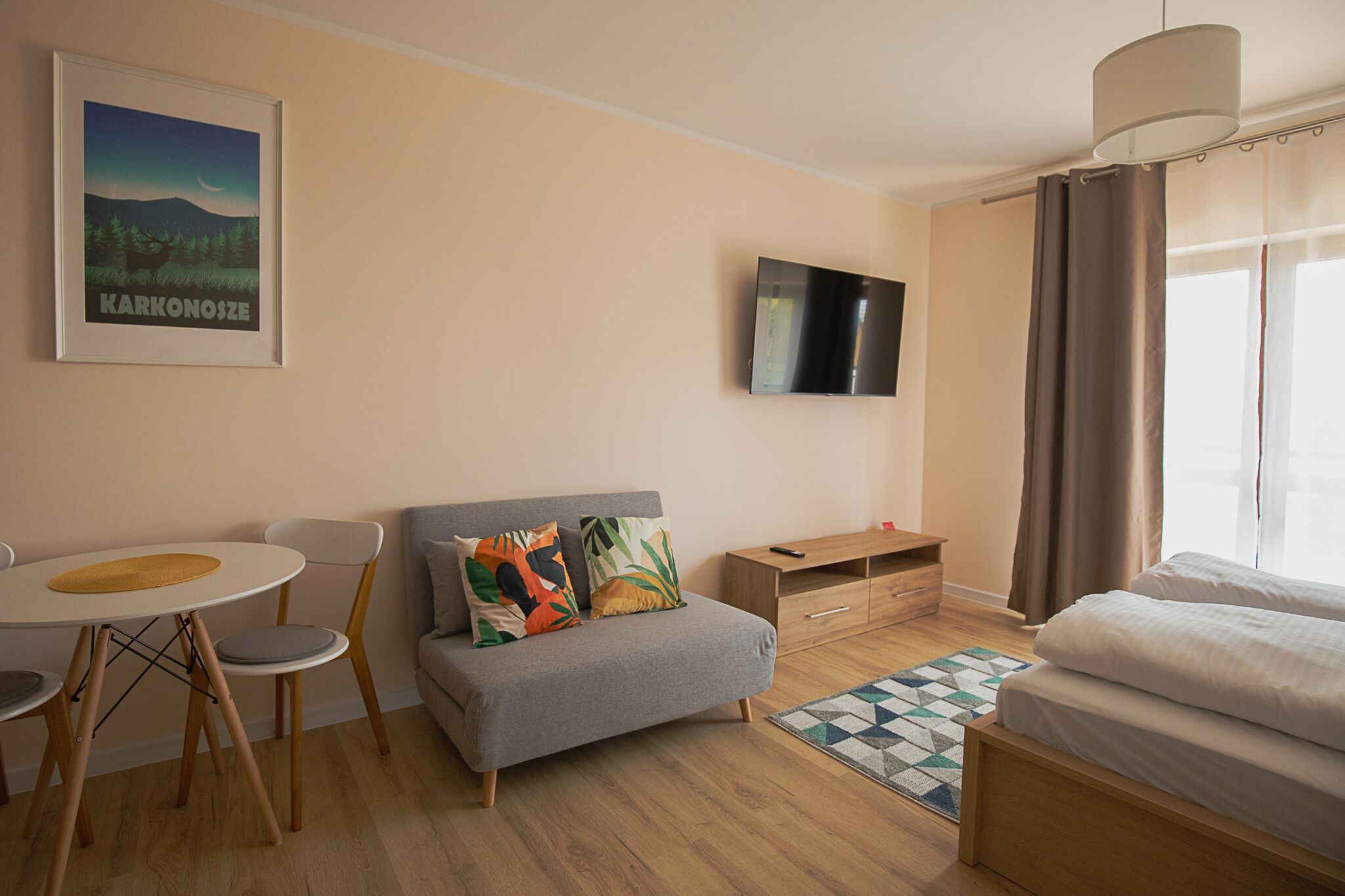 A modern hotel room with a sofa, a small table, a TV, and a bed.