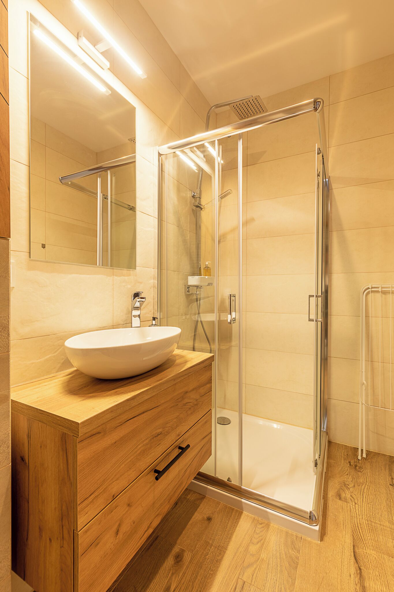 Une salle de bain moderne avec un meuble-lavabo en bois, une cabine de douche en verre et un grand miroir.