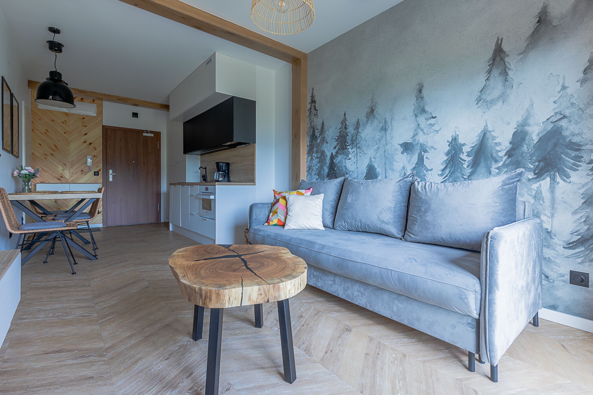 A modern living room with a grey sofa, a wooden coffee table, and a dining area with a wooden table and chairs.