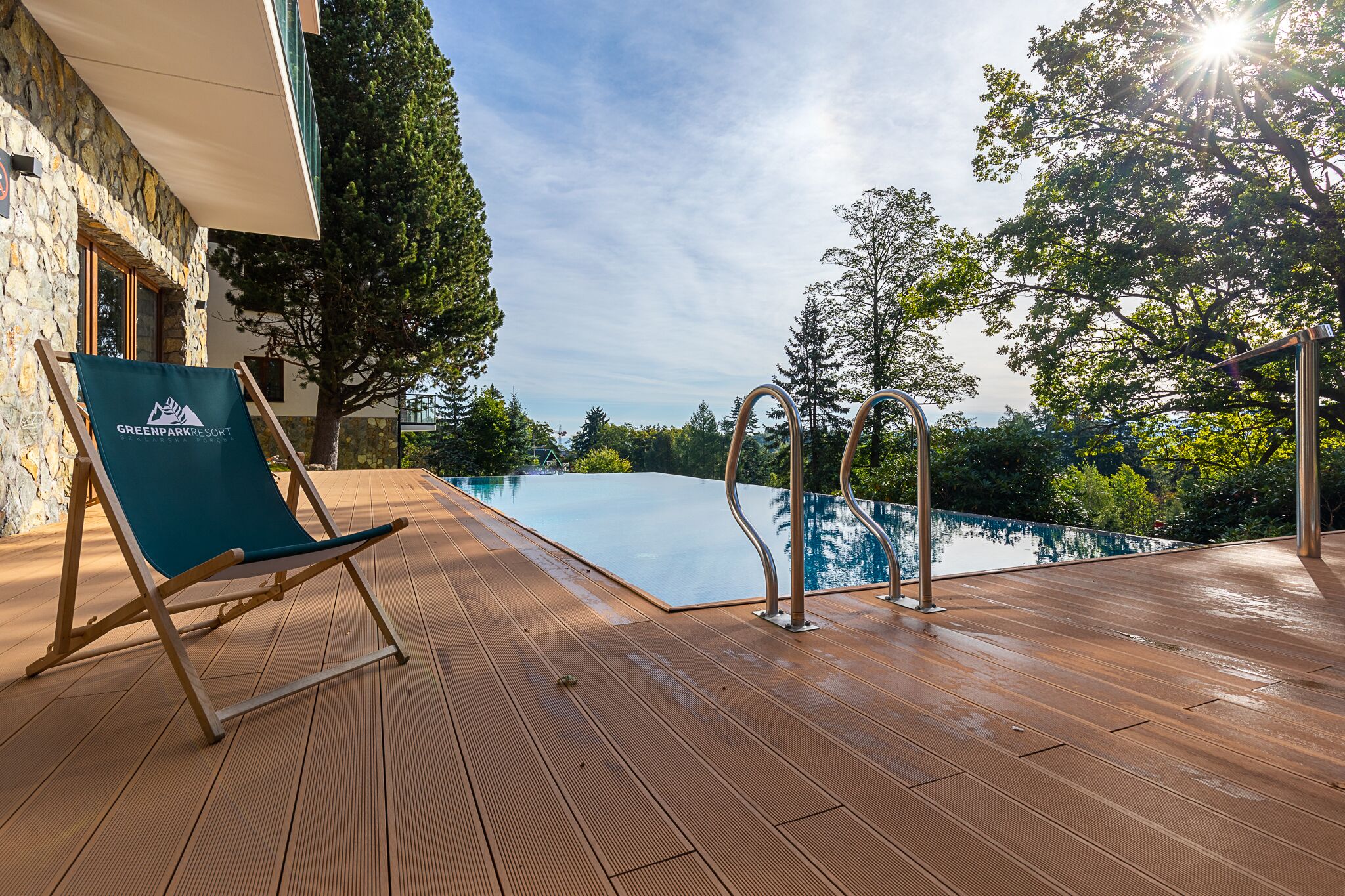 Um deck de madeira com espreguiçadeira e área ao lado da piscina no Greenpark Resort.