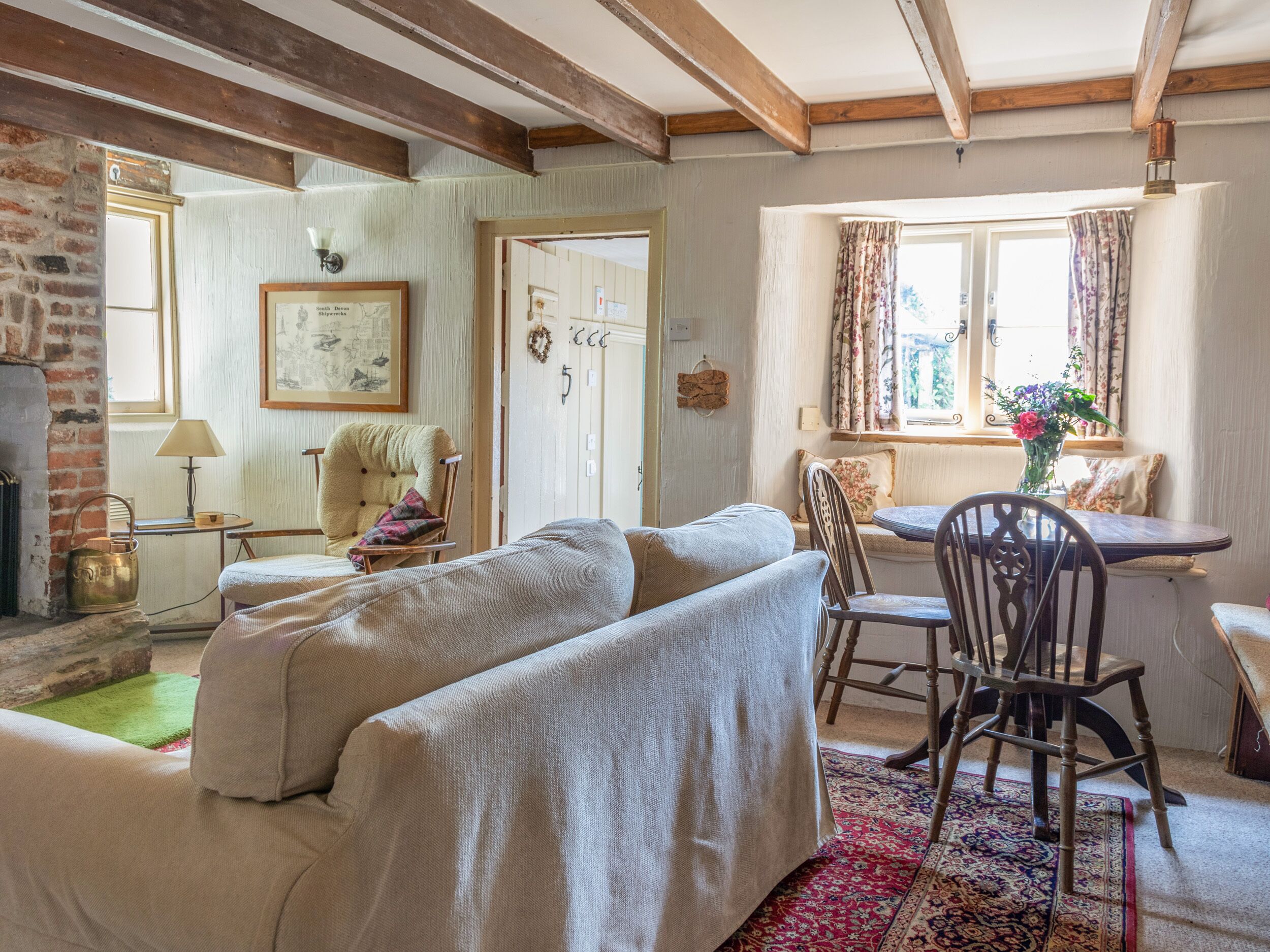 Uma sala de estar aconchegante com lareira, uma área de jantar com mesa e cadeiras, e uma janela grande com cortinas.