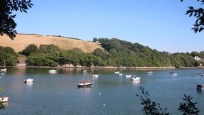 A calm lake with several boats, surrounded by hills and trees. - End Cottage (Kingsbridge)