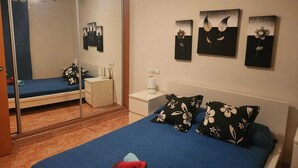 Une chambre à coucher comprenant un lit, une table de chevet, un miroir et des œuvres d’art murales.