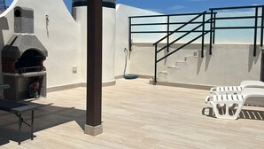 Une terrasse sur le toit équipée d’un barbecue, de meubles d’extérieur et offrant une vue dégagée sur le ciel.