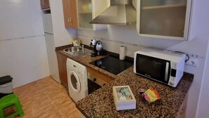 Une cuisine compacte équipée d’un lave-linge, d’un four à micro-ondes, d’un évier et de placards.