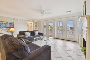 A spacious living room with a ceiling fan, a glass coffee table, and two sofas.