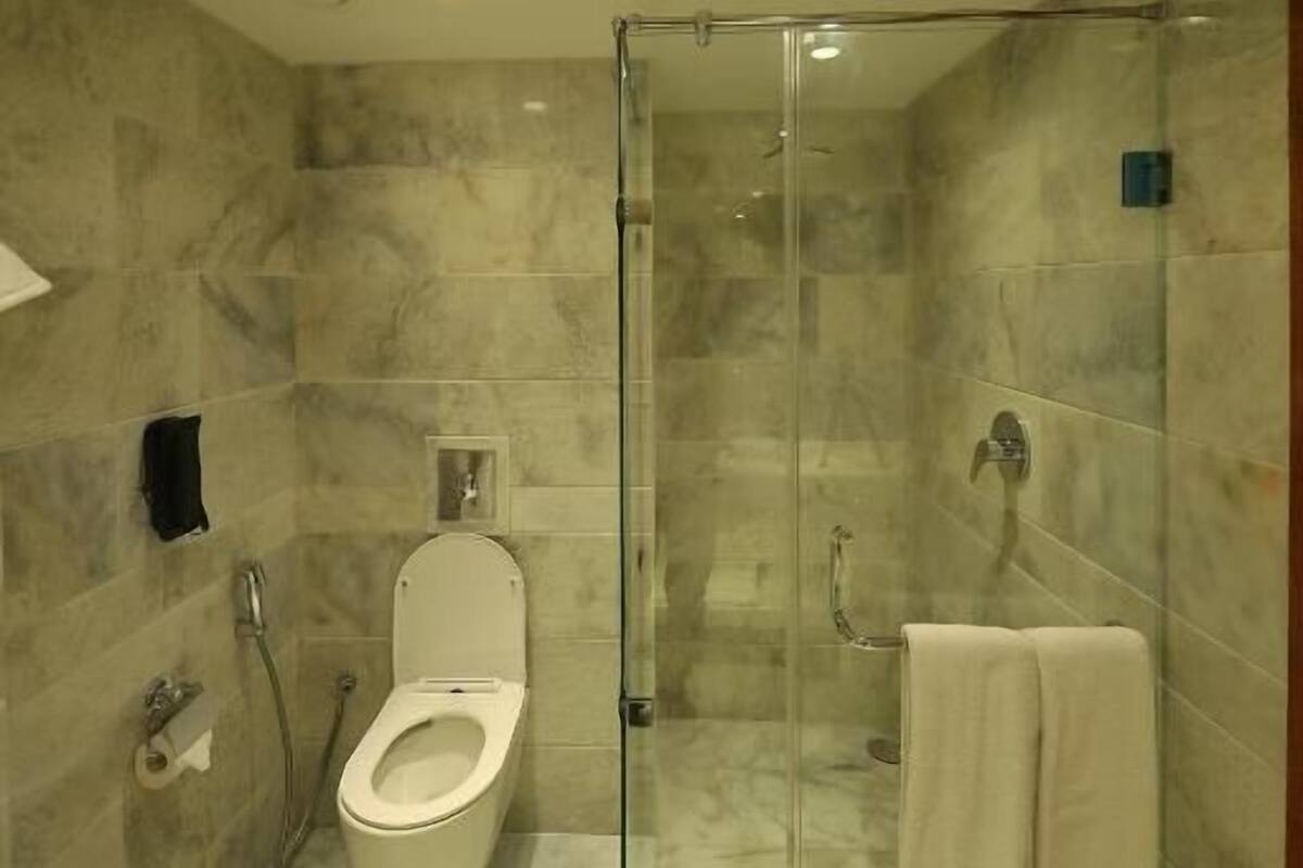 A modern bathroom with a glass-enclosed shower, a toilet, and a towel rack.
