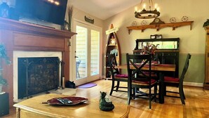 A living room with a fireplace, a television, a dining area with chairs and a table, and a chandelier. - Quail cove 1616 at Rumbling Bald (Lake Lure)