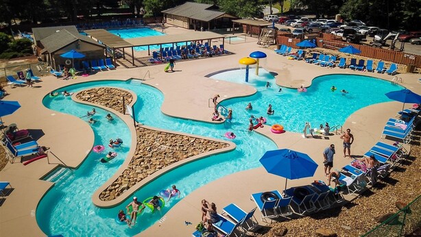 A large outdoor swimming pool with multiple lanes and a separate kiddie pool, surrounded by lounge chairs and umbrellas. - Quail cove 1616 at Rumbling Bald (Lake Lure)