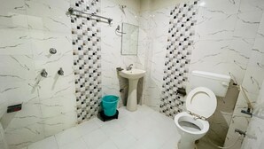 Une salle de bain avec des murs en marbre blanc, un lavabo, des toilettes et un espace douche.