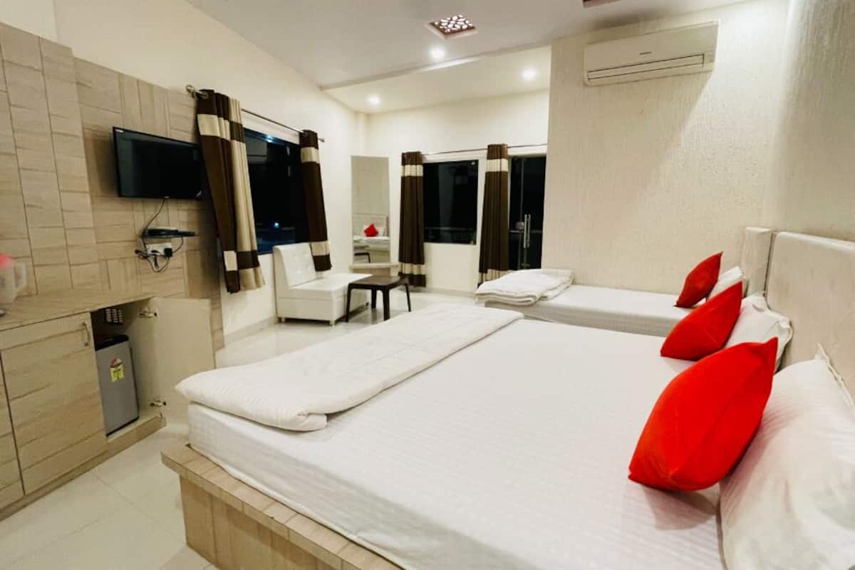 Habitación de hotel con dos camas, televisión, escritorio y baño.