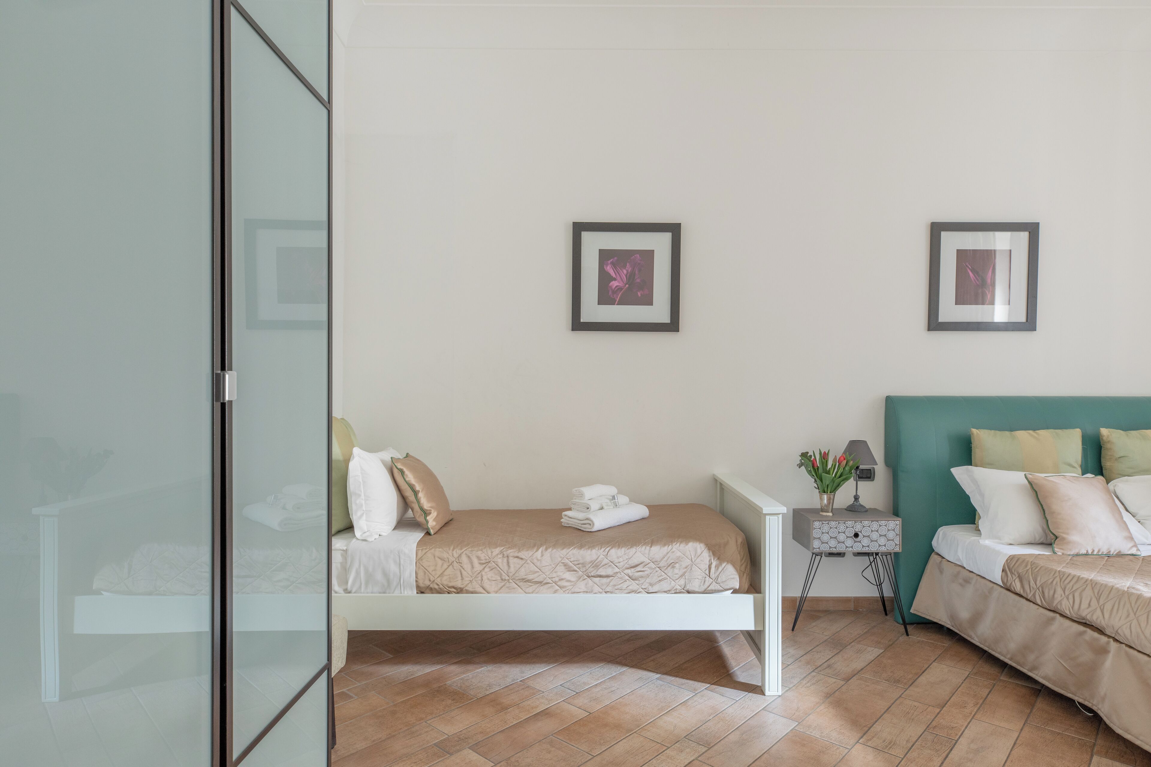 Une chambre moderne avec un lit simple, une table de chevet et une commode. Deux tableaux encadrés ornent le mur.