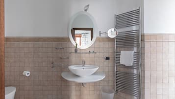 Une salle de bain avec un lavabo blanc, un miroir, un porte-serviettes et des toilettes.