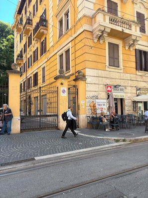 Una calle con un edificio amarillo, un bar y mesas al aire libre.