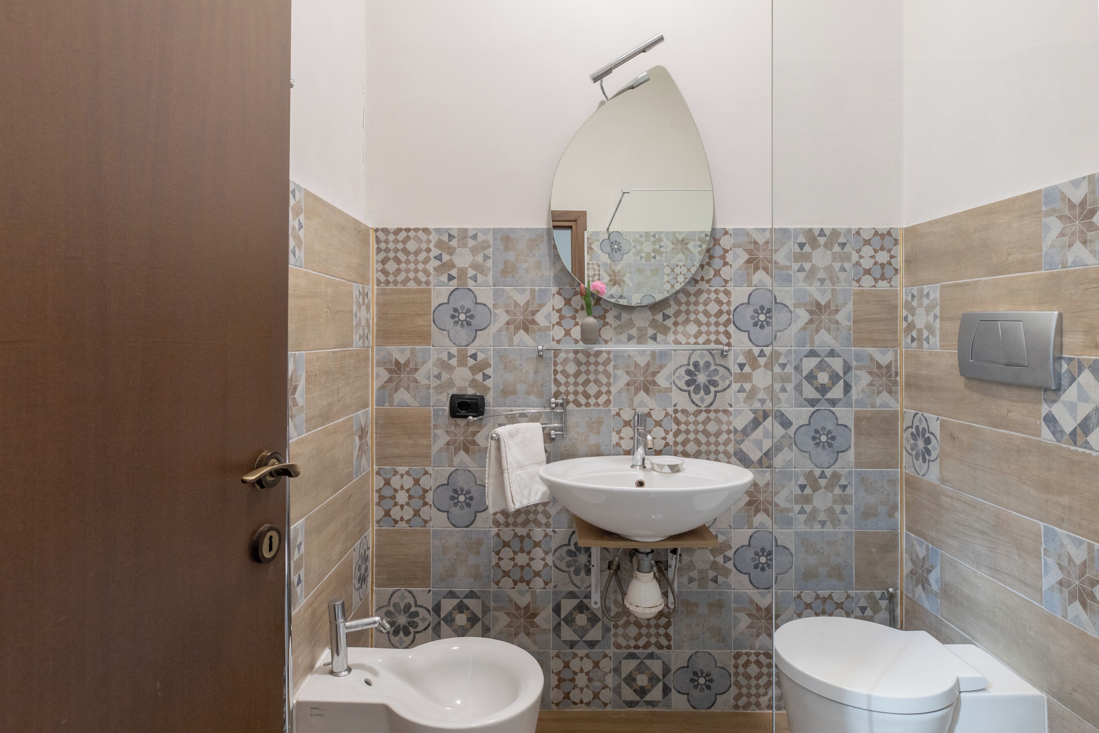 Une salle de bain équipée de toilettes, d’un bidet, d’un lavabo et d’un miroir.
