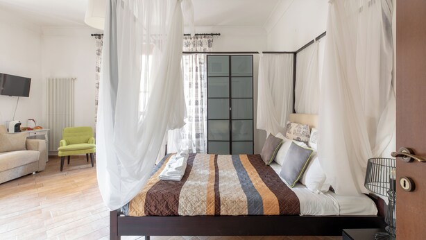 A bedroom with a bed, a chair, a TV, and a wardrobe. - Flaminiarooms (Rome)