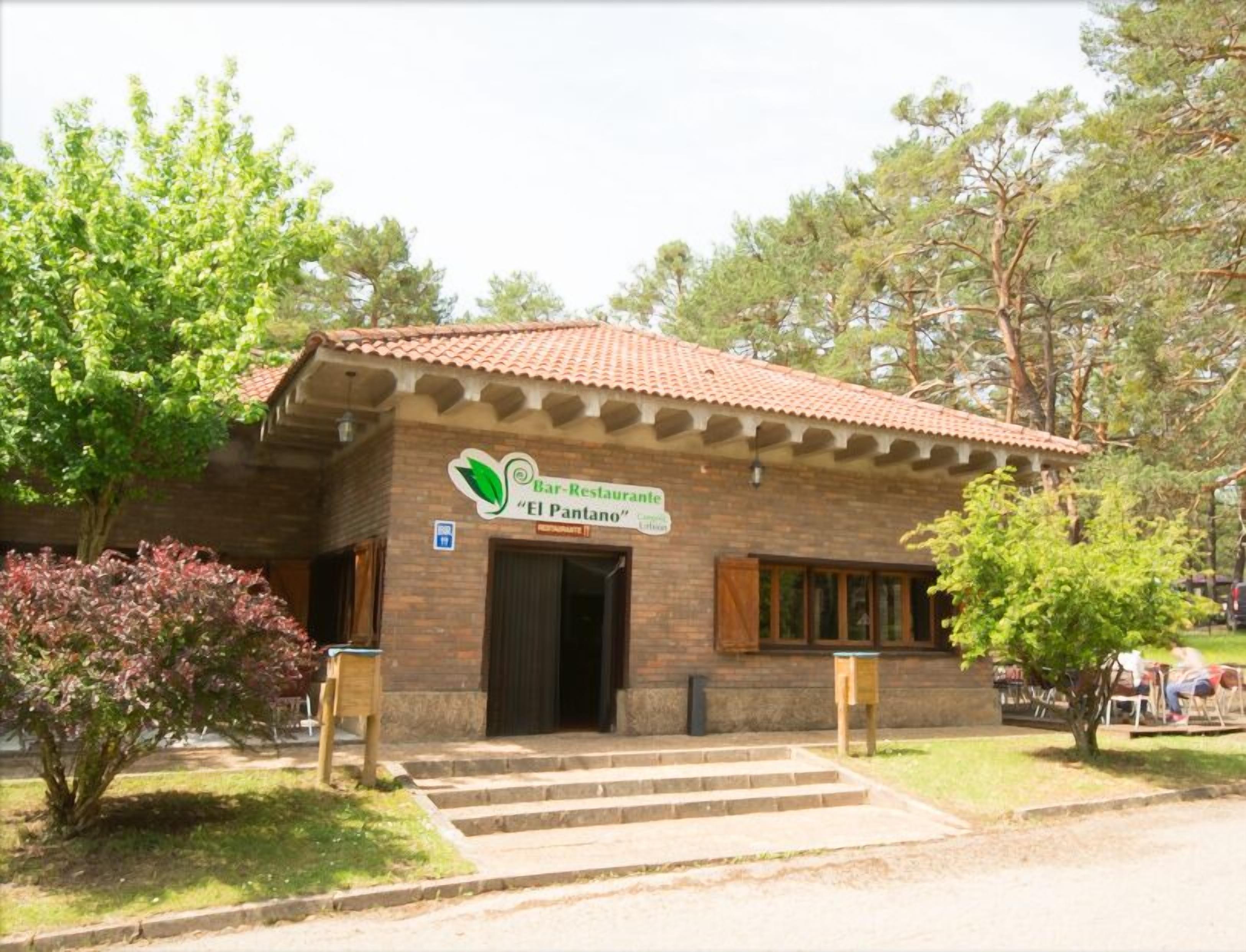 A brick building with a tiled roof and a sign reading "Bar-Restaurante 'El Pantano'".