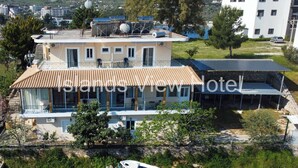 A two-story hotel with a tiled roof, a pool, and a view of the surrounding landscape. - Islands View Hotel (Ksamil)