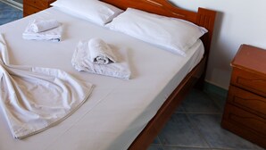 A neatly made bed with white linens and towels, a wooden headboard, and a wooden nightstand with drawers. - Islands View Hotel (Ksamil)