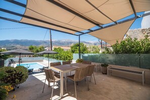 Um pátio externo com piscina, área de estar e vista para montanhas.