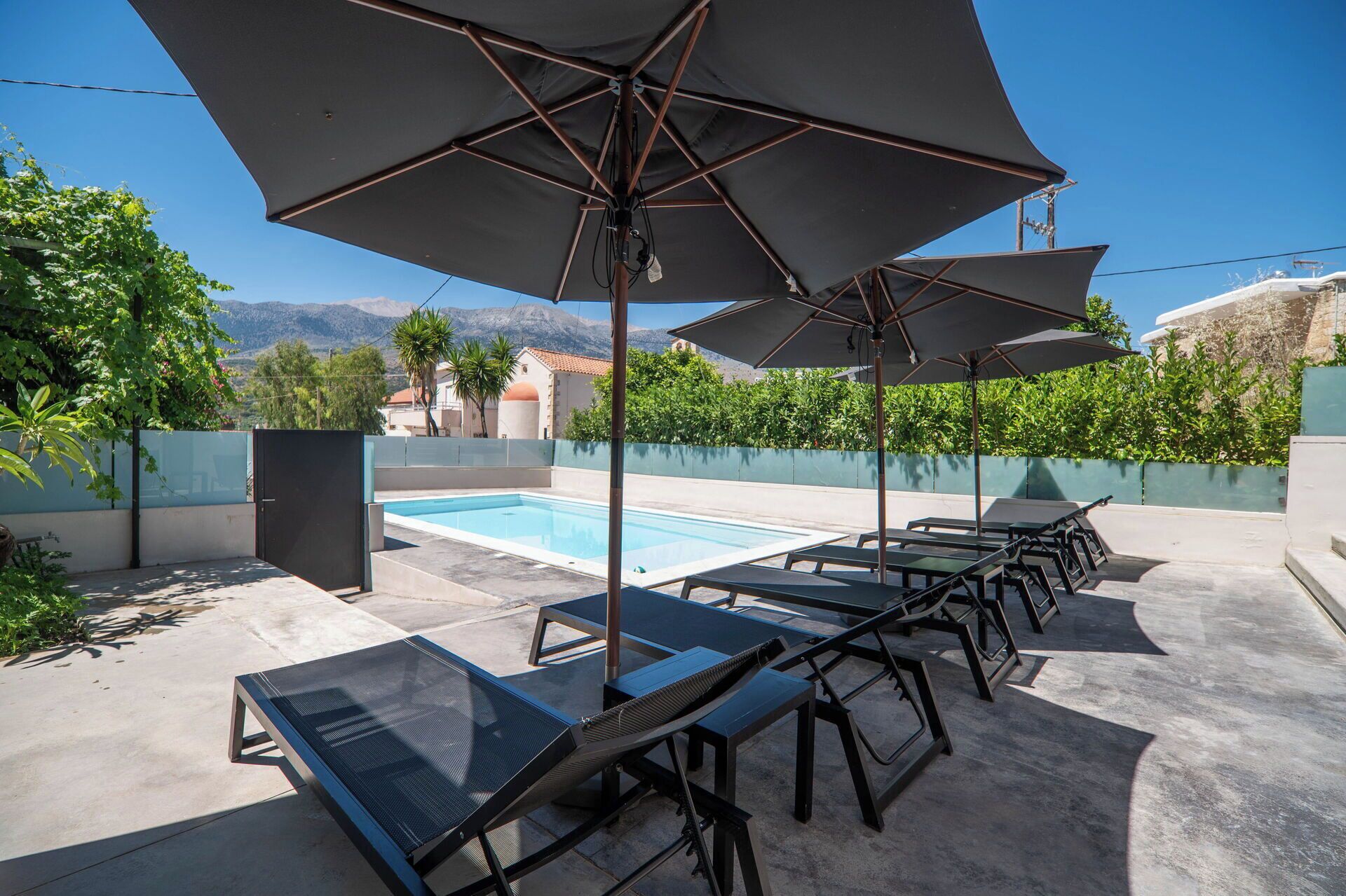 Area piscina con lettini e ombrelloni, una piscina e vista sulle montagne.