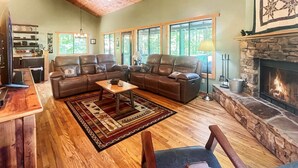 Una sala de estar acogedora con sofás de cuero, una mesa de centro y una chimenea de piedra.