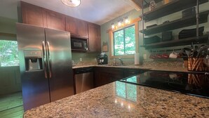 Una cocina moderna con encimeras de granito, electrodomésticos de acero inoxidable y un ventanal que proporciona luz natural.