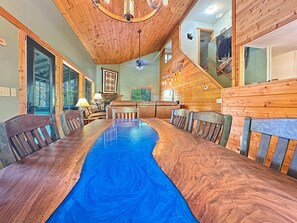 A wooden interior with a long dining table, chairs, and a ceiling fan. - Bear's Den - Nantahala Gorge seclusion and convenience + free rafting (Bryson City)