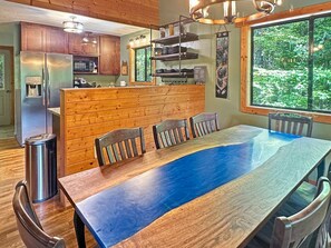 Een moderne keuken met houten kastjes, een roestvrijstalen koelkast en een eethoek met een grote tafel en stoelen.