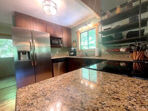 A kitchen with granite countertops, stainless steel appliances, and wooden cabinets.