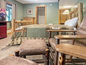 A room with a bed, a wooden chair, a small table, a red cabinet, and a painting on the wall. - Free rafting and zip line tix - convenient Nantahala Gorge location sleeps 10 (Bryson City)