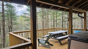 A covered deck with picnic tables and benches, surrounded by trees.