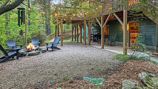 A cozy outdoor seating area with Adirondack chairs and a fire pit, surrounded by trees and a wooden deck. - Bear's Den Max - 4 bedrooms in the Nantahala Gorge - free rafting or other (Bryson City)