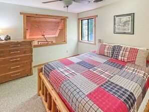A bedroom with a wooden bed, a dresser, a window with blinds, and a ceiling fan.