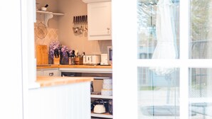 Una cocina con armarios blancos, encimera de madera y diversos utensilios de cocina.