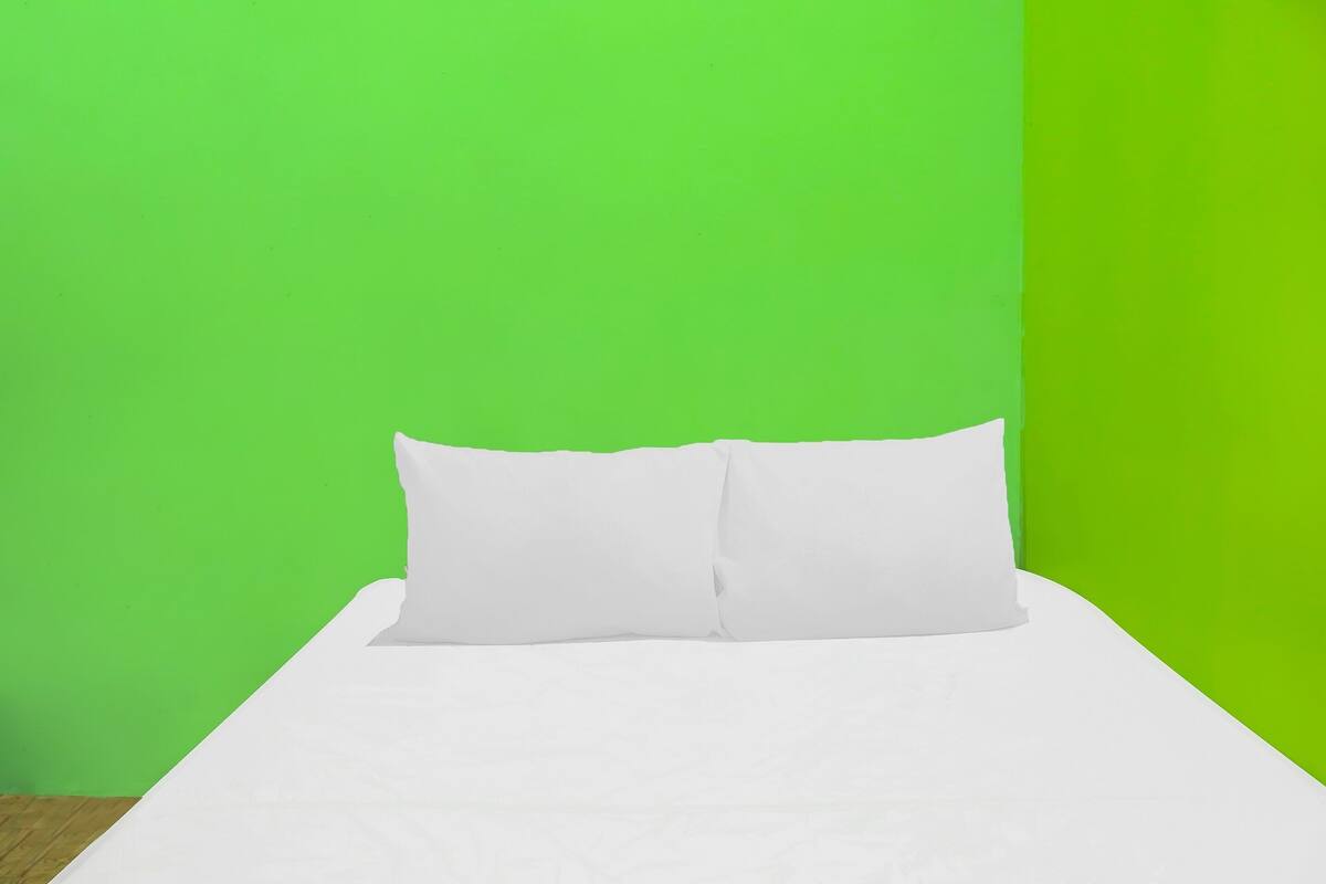 A bed with white bedding in a room with green walls.