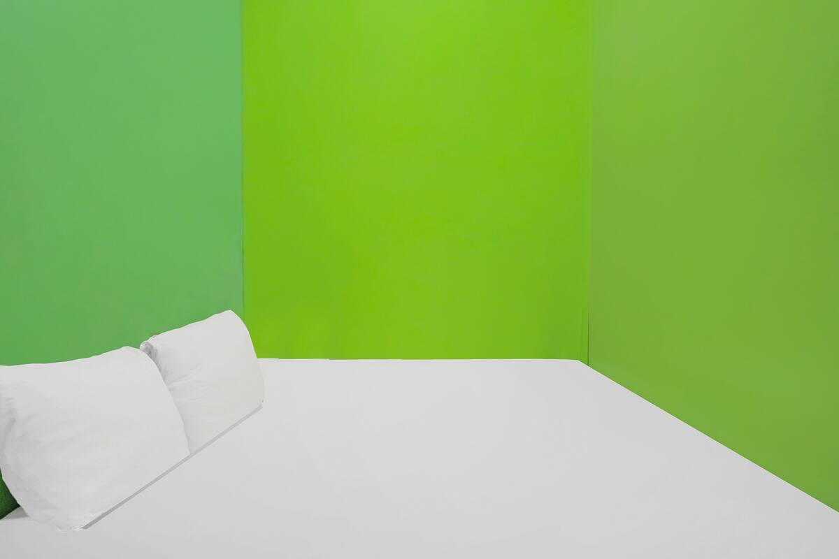 A room with a bed against a green wall.
