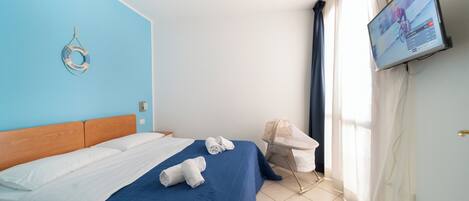 Habitación de hotel con cama, televisor, una silla y un flotador en la pared.