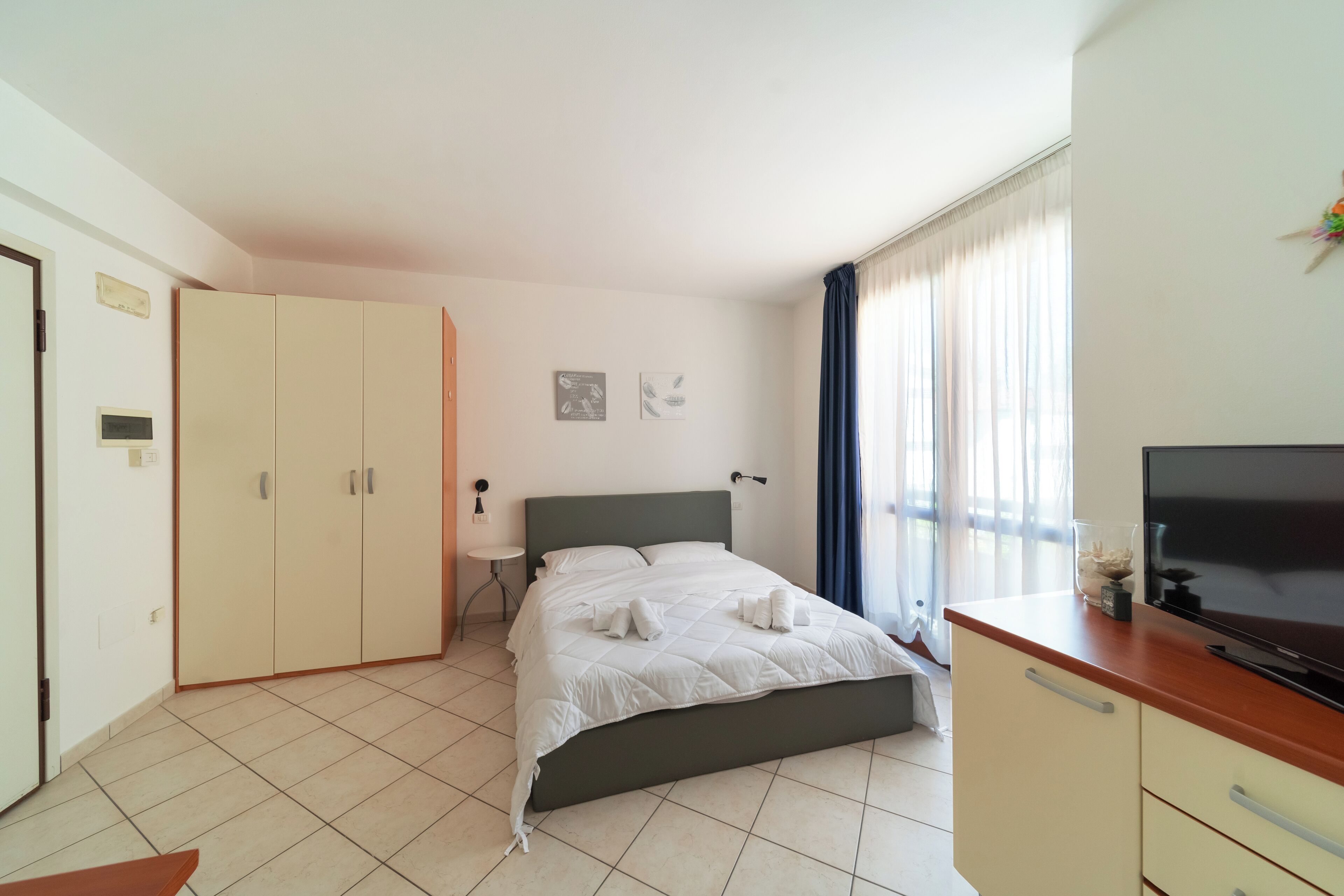 A bedroom with a bed, a wardrobe, a TV, and a bedside table.