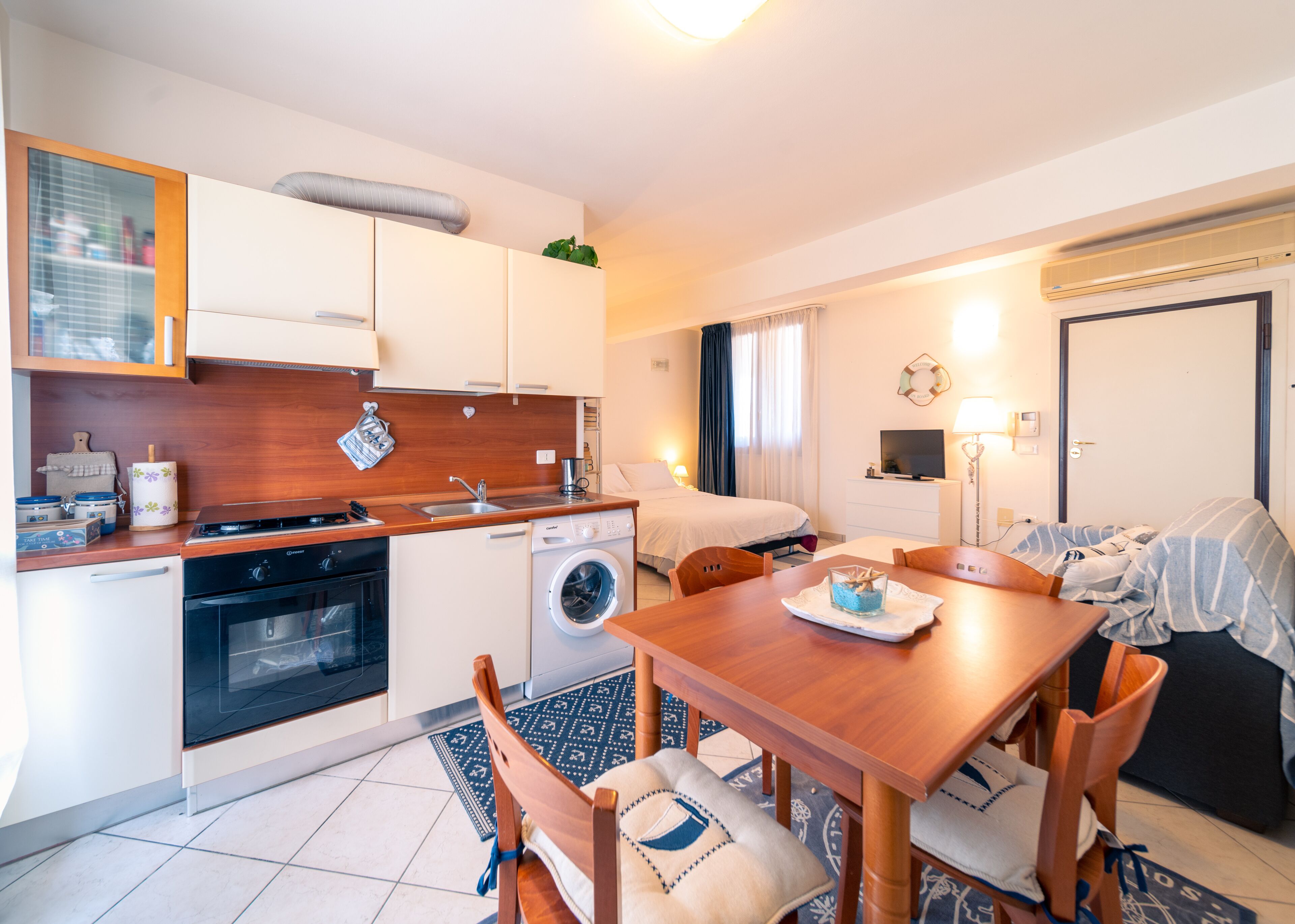 Une chambre d’hôtel compacte comprenant un coin cuisine, un espace repas, un lit et une salle de bain.