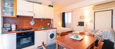 Une chambre d’hôtel compacte comprenant un coin cuisine, un espace repas, un lit et une salle de bain.