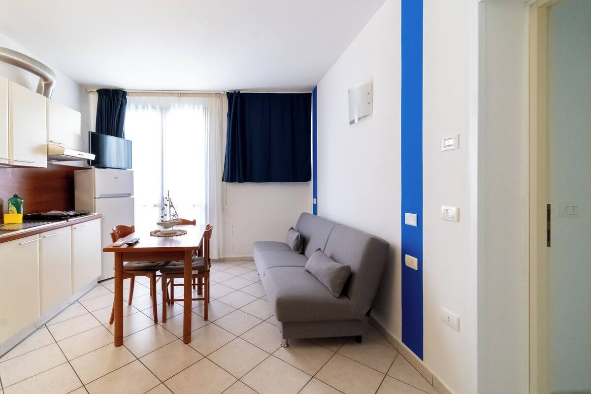 A compact living space with a kitchenette, a dining area, and a sofa.