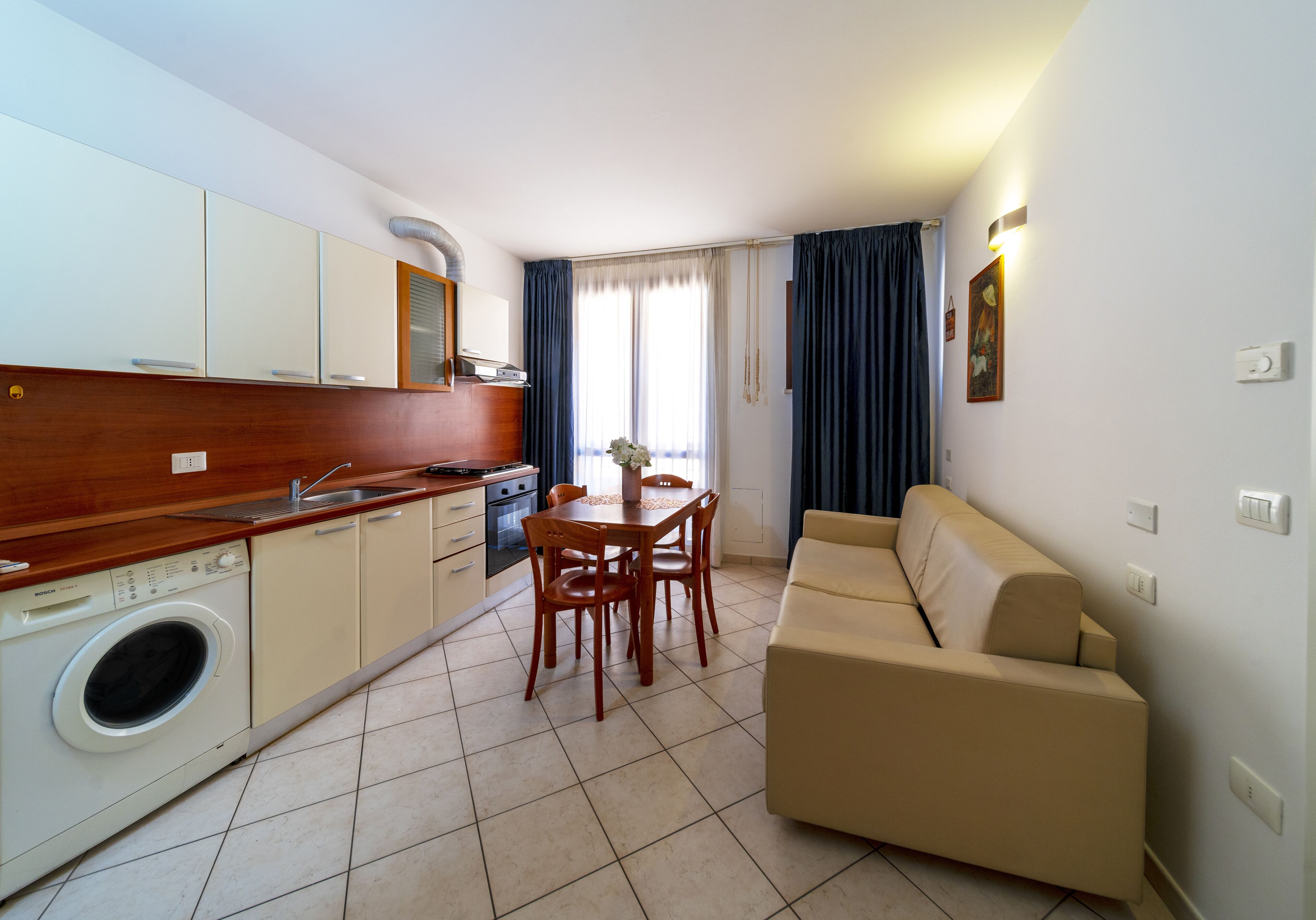 Un espacio habitable compacto con kitchenette, comedor y sofá.