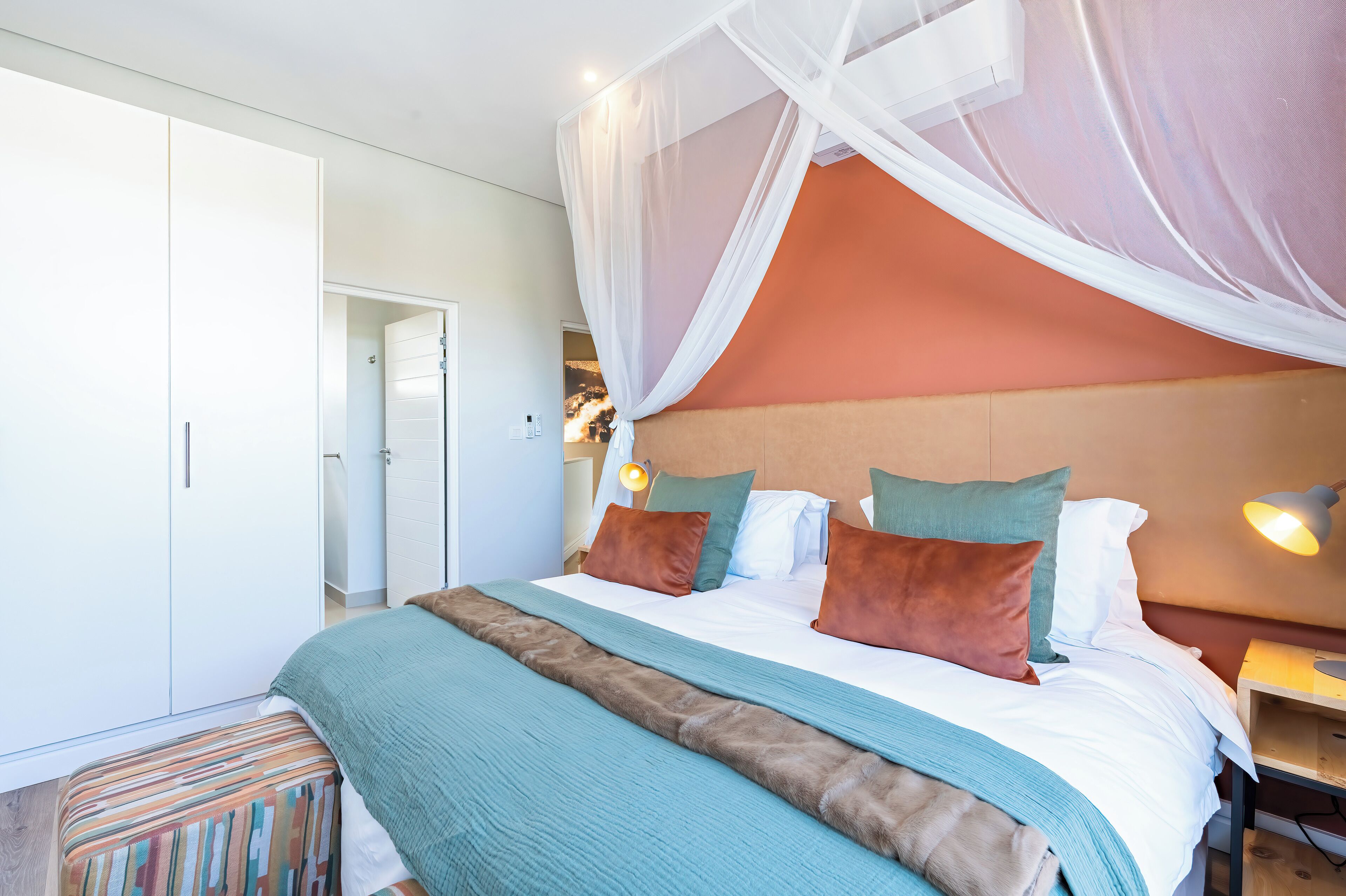 A bedroom with a bed, a nightstand, a lamp, and a wardrobe.